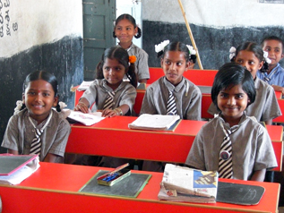 公立学校に新しく揃えられた赤い机で勉強する子どもたち